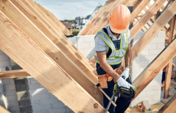 busy-construction-site-worker-wearing-protective-equipment-using-chainsaw-cut-wood-building